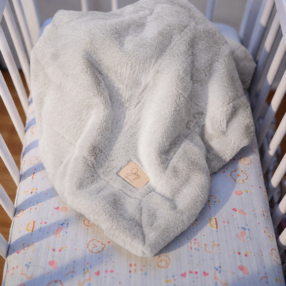 Gray textured blanket on a crib with colorful bedding underneath